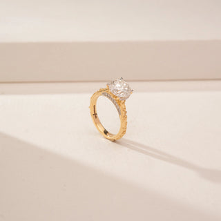 Angled view of a 14KT Yellow Gold diamond ring, featuring a round centre diamond and diamond-set inner band.