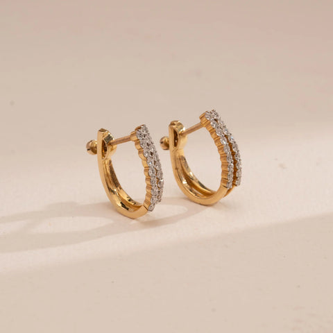 Angled view of Reia’s 14 KT Yellow Gold Double Row Pavé Diamond Hoops. The layout highlights the contemporary parallel bands of pavé-set round diamonds against a clean, cream backdrop.