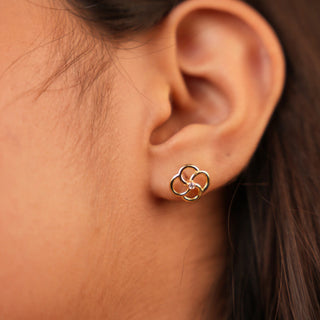 Woman wearing a delicate floral stud earring featuring a central round lab-grown diamond, forming a soft petal-inspired silhouette. 