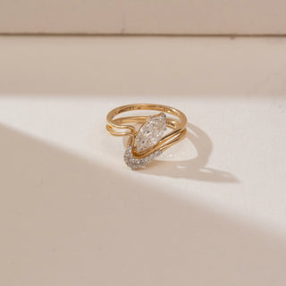 Top angle view of 14KT yellow gold wave ring featuring a marquise-cut centre diamond and layered flowing bands with pavé-set diamond accents on the lower curve.