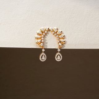 Front view of diamond ear climber earrings in 14 KT Yellow Gold, featuring pear-shaped diamonds in a graceful curved arrangement with dangling pear halo drops against a neutral backdrop.
