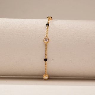 Front view of a 14KT Yellow Gold bracelet with chain links, black beads and round bezel-set diamond stations.