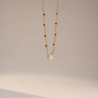 Angled view of a yellow gold lab-grown diamond mangalsutra featuring a round halo diamond pendant on a delicate black bead chain, displayed on a neutral background.