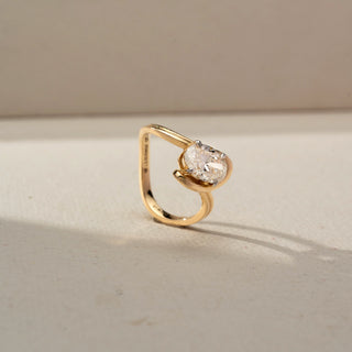 Side view of a contemporary yellow gold ring featuring an oval-cut solitaire diamond in a sculptural wraparound setting, highlighting the elevated profile and elegant curves.