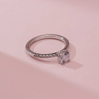 Top view of Reia’s 14 KT White Gold Lustreline Classic Solitaire Diamond Ring, showing a round stone on a pavé band. Set against pink, it highlights high-shine, timeless elegance.