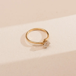 Top view of Reia’s 14 KT Yellow Gold Timeless Single Stone Diamond Ring. It highlights the brilliant round solitaire diamond and the sleek, minimal band design against a clean, cream backdrop.