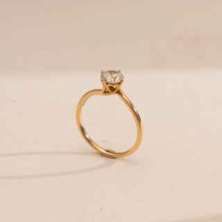 Side view of Reia’s 14 KT Yellow Gold Timeless Single Stone Diamond Ring. It highlights the brilliant round solitaire diamond and the sleek, polished band on a cream backdrop.
