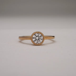 Front view of Basket Solitaire Diamond Engagement Ring in yellow gold, displayed on a grey surface. The round solitaire diamond, bezel-set with milgrain detailing, shines with EF colour and VVS clarity. Crafted in 14KT gold, weighing 2.57 grams, with a 0.54 carat solitaire for timeless elegance.