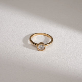 Flat lay of Basket Solitaire Diamond Engagement Ring in yellow gold, photographed on a grey surface. Features a bezel-set round solitaire diamond with milgrain edging, crafted in 14KT hallmarked gold. Diamond weighs 0.54 carats, EF colour, VVS clarity. The 2.57-gram slim band highlights minimal elegance.