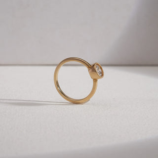 Side profile of Basket Solitaire Diamond Engagement Ring in yellow gold on a grey surface. The raised bezel-set solitaire with milgrain detail enhances its brilliance. Crafted in 14KT hallmarked gold, weighing 2.57 grams, the 0.54 carat EF VVS diamond offers a refined and timeless appeal.