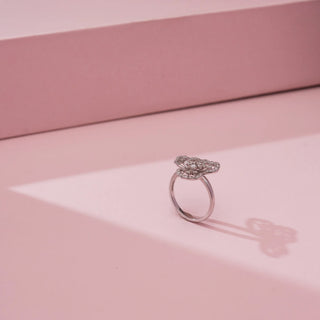 Side view of Reia’s 14 KT White Gold Blooming Clover Diamond Statement Ring. Captured on a pink backdrop, it highlights the sleek foundation and contemporary, nature-inspired silhouette.