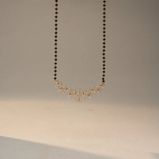 Front view of a yellow gold lab-grown diamond mangalsutra featuring a cascading leaf-inspired diamond pendant on a classic black bead chain, displayed on a neutral background.