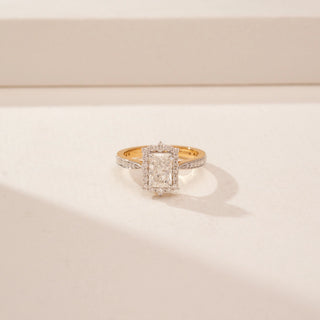 Close up view of a 14KT Yellow Gold diamond ring, featuring an emerald-cut centre diamond and diamond halo.