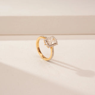 Angled view of a 14KT Yellow Gold diamond ring, featuring an emerald-cut centre diamond and diamond halo.