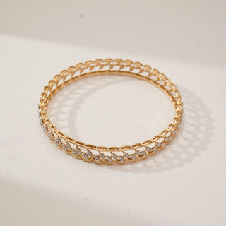 Top angled view of yellow gold diamond bangle featuring marquise leaf-inspired links set with round lab-grown diamonds, forming a continuous delicate pattern on a soft neutral background.