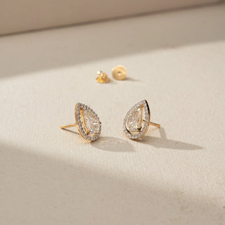 Angled view of pear-shaped diamond halo stud earrings in yellow gold, highlighting the sparkling center stones, pavé halo, elevated setting, and post-back design.