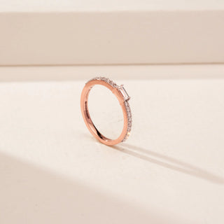 Angled view of a 14KT Rose Gold diamond ring, featuring a rectangular emerald-cut diamond and diamond-set band.