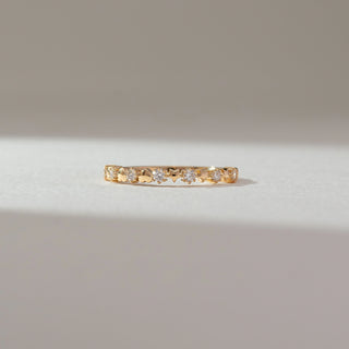 Front view of heart motif diamond band ring in yellow gold, featuring alternating heart shapes and round lab-grown diamonds along the band. Set on a soft neutral backdrop, it reflects playful elegance.