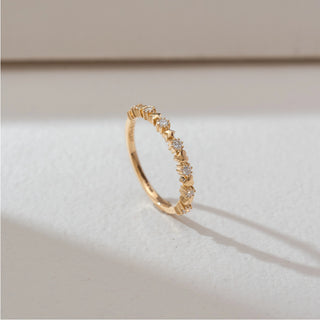 Side angled view of heart motif diamond band ring in yellow gold, featuring alternating heart shapes and round lab-grown diamonds along the band. Set on a soft neutral backdrop, it highlights delicate detail and sparkle.
