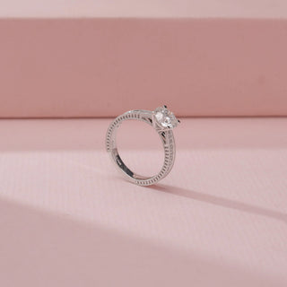 Angled view of a 14KT White Gold diamond ring with a round centre stone and double pavé-set band.