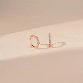 Angled view of 14KT rose gold hoop earrings, featuring pavé-set round lab-grown diamonds along the front of each hoop.