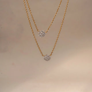 Front view of a floral diamond pendant necklace in 14 KT Yellow Gold, featuring round diamond flower cluster motifs suspended on a delicate double-layer chain against a soft neutral backdrop.
