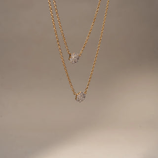 Side view of a floral diamond pendant necklace in 14 KT Yellow Gold, featuring round diamond flower cluster motifs suspended on a delicate double-layer chain against a soft neutral backdrop.
