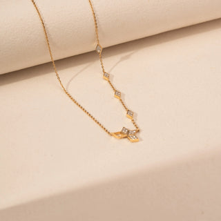 Angled view of a geometric lab-grown diamond necklace in 14KT Yellow Gold, featuring open hexagonal motifs with bezel-set diamonds. Captured against a beige backdrop, the contemporary design exudes minimalist elegance.