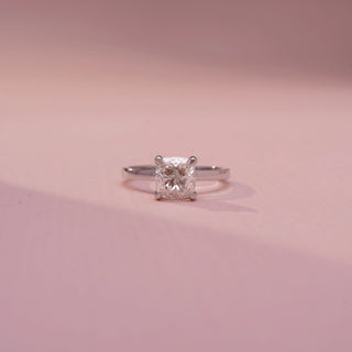 Front view of a cushion-cut solitaire ring in White Gold, featuring a cushion-cut lab-grown diamond in a classic four-prong setting, displayed against a soft pink backdrop.