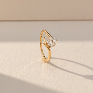 Side view of Pear Solitaire Diamond Ring in 14KT Yellow Gold, featuring a centred pear-shaped lab grown diamond in prong setting. Set on a beige backdrop, the design highlights structure and elegant curves.
