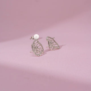 Side view of a 14KT white gold earrings featuring round-cut diamonds in a butterfly-inspired design, set against a pink background.