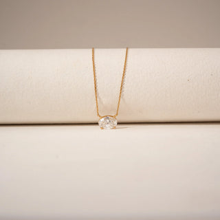 Close-up view of an oval-cut diamond pendant in 14KT Yellow Gold with a delicate gold chain and minimal setting.