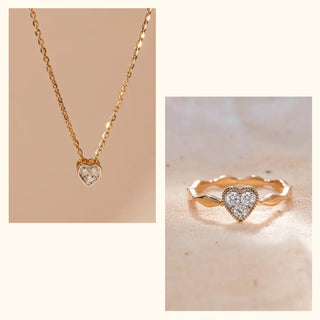 Gold Weight and Purity of the set: Crafted in 14 KT Yellow Gold. Necklace weighs 2.724 grams. Ring weighs 1.67 grams.

Diamond Weight and Clarity: Necklace 0.07 carats (0.023 ct max) round solitaire diamond in a heart frame. Ring 0.15 carats (0.05 ct max) round diamonds in a heart-shaped cluster band with milgrain detailing.

Background of the jewelry: The necklace (a heart solitaire pendant on a chain) and the matching heart-cluster ring are displayed on a smooth, lightly textured, light beige background w