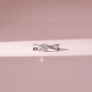 Front view of a twisted solitaire diamond ring in14 KT white gold, featuring a round centre diamond and sculpted crossover shoulders.