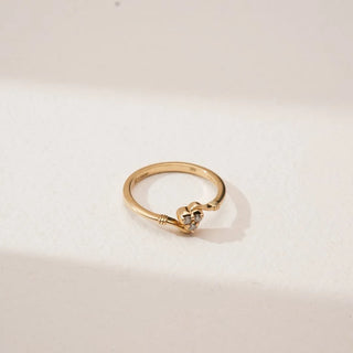 Top angled view of Golden Heart Trio Diamond Ring in yellow gold, featuring a heart-shaped motif set with three round lab-grown diamonds on a slender polished band against a neutral backdrop.
