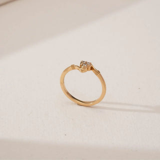 Side angled view of Golden Heart Trio Diamond Ring in yellow gold, highlighting the sculpted heart motif with three round lab-grown diamonds set on a slender polished band against a neutral surface.
