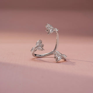 Front view of a floral wrap ring in White Gold, featuring marquise-shaped lab-grown diamond clusters arranged along an open-ended spiral band, displayed against a soft pink backdrop.