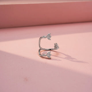 Side view of a floral wrap ring in White Gold, featuring marquise-shaped lab-grown diamond clusters arranged along an open-ended spiral band, displayed against a soft pink backdrop.