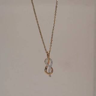 Front view of Infinity Loop Golden Diamond Pendant in yellow gold, featuring intertwined infinity curves set with round lab-grown diamonds and a subtle dangling accent, displayed against a soft beige backdrop.