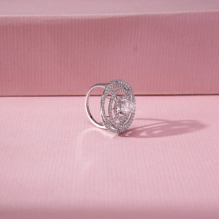 Angled view of spiral halo diamond ring in white gold, featuring a centred round lab-grown diamond within layered pavé-set circular loops. Set against a soft pink background, the design casts a refined shadow.