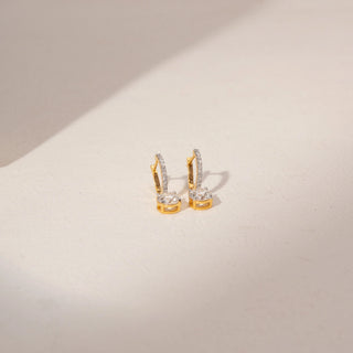 Angled view of diamond drop earrings in 14KT yellow gold, featuring pavé hoops and round lab-grown diamond drops.