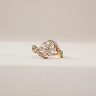 Front view of Pear Petal Cluster Diamond Ring in yellow gold, featuring pear-shaped lab-grown diamonds arranged in a floral cluster with a diamond-studded bypass band on a soft neutral surface.
