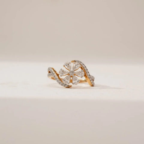 Front view of Pear Petal Cluster Diamond Ring in yellow gold, featuring pear-shaped lab-grown diamonds arranged in a floral cluster with a diamond-studded bypass band on a soft neutral surface.