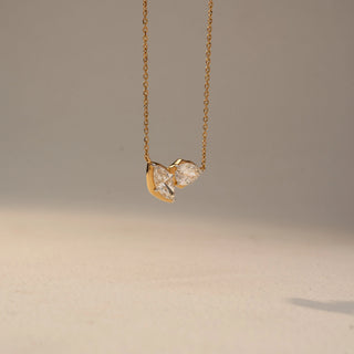 Side view of a marquise diamond necklace in 14 KT Yellow Gold, featuring two marquise-cut lab-grown diamonds arranged in a graceful V-shaped design, suspended from a delicate chain against a beige backdrop