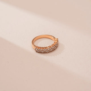 Top view of Reia’s 14 KT Rose Gold Eternal Glow Diamond Band Ring. A continuous row of pavé-set round diamonds creates a radiant glow on a warm gold band against a soft pink surface.