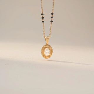 Front view of a diamond mangalsutra pendant in Dual gold, featuring an oval-cut centre diamond with textured oval detailing on a delicate black bead chain.