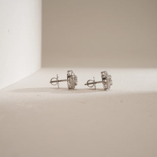 Side view of Cluster Halo Diamond Stud Earrings on beige background. Crafted in 14KT hallmarked white gold with bombay screw closure. Features EF colour, VVS clarity lab grown diamonds totaling 1.42 carats, including a 0.47-carat solitaire. Product weighs 3.43 grams, priced INR 50,000–1,00,000.
