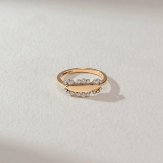 Top view of oval halo diamond ring in yellow gold, featuring an open oval centre with round lab-grown diamonds set along both edges of the band. Set on a soft neutral surface, it reflects minimal elegance and sparkle.