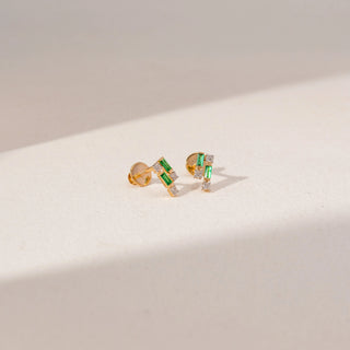 Angled view of Emerald Diamond Earrings in 14KT Yellow Gold, featuring baguette-cut green gemstones and round lab-grown diamonds.