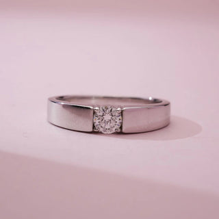 Front close view of Elegant Minimalist Radiant Diamond Ring in white gold, featuring a single round lab-grown diamond set within a sleek flat band, displayed on a soft pink background.